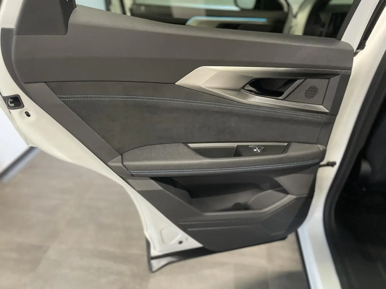 Porte arrière gauche ouverte du Renault Austral blanc nacré satin, garniture noire avec surpiqûres bleues et insert aluminium.