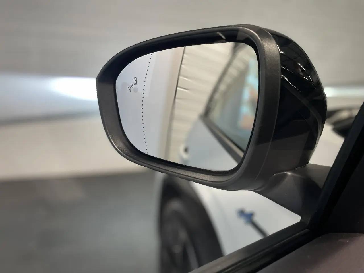 Rétroviseur extérieur droit noir brillant du Renault Austral blanc nacré satin avec toit noir étoilé, vue rapprochée.