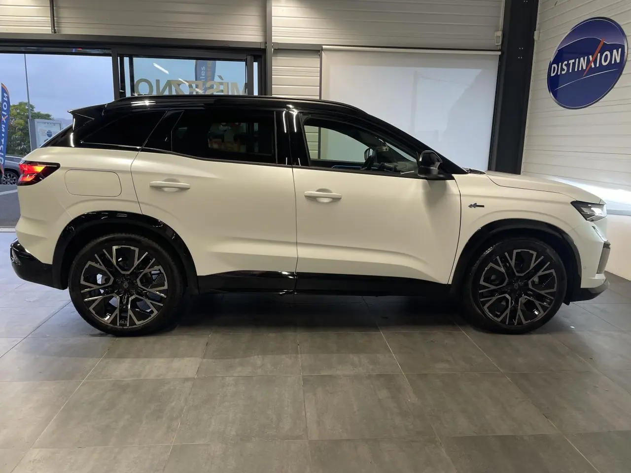 Profil droit du Renault Austral 2025 blanc nacré satin avec toit noir et jantes alliage noires en showroom.