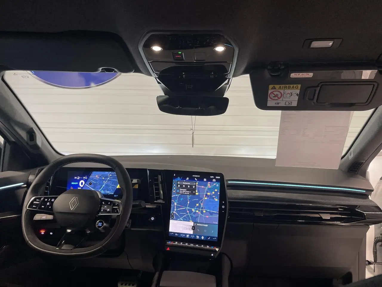 Vue frontale de l'intérieur du Renault Austral 2025, tableau de bord noir avec écran tactile vertical et volant multifonction.