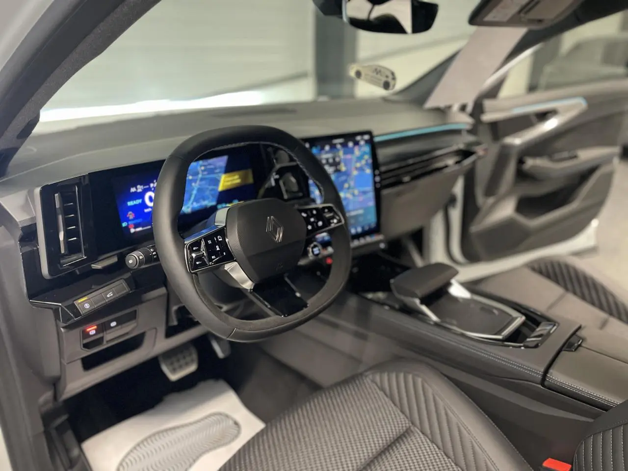 Intérieur Renault Austral 2025 vu côté conducteur, volant Alcantara, écran tactile vertical et sellerie tissu carbone.