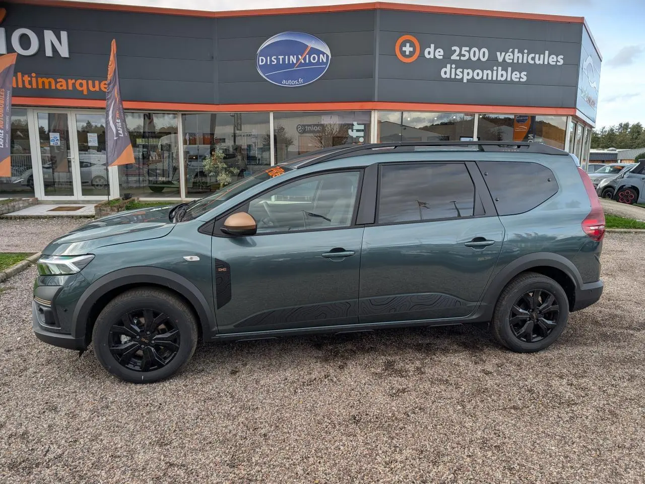 Vue latérale droite d'un Dacia Jogger 2025 vert métallisé avec jantes noires et rétroviseurs cuivrés.