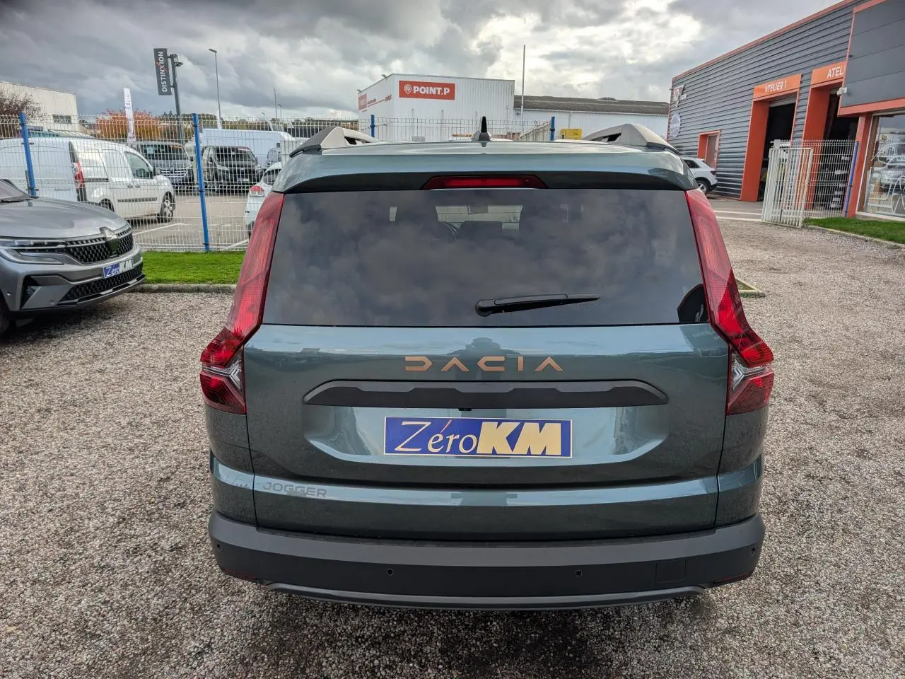 Vue arrière d'un Dacia Jogger vert métallisé avec logo brun cuivré et feux arrière verticaux distinctifs.