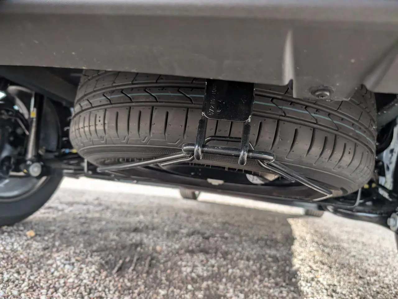 Gros plan sous le véhicule montrant la roue de secours suspendue du Dacia Jogger 2025, détail mécanique visible.