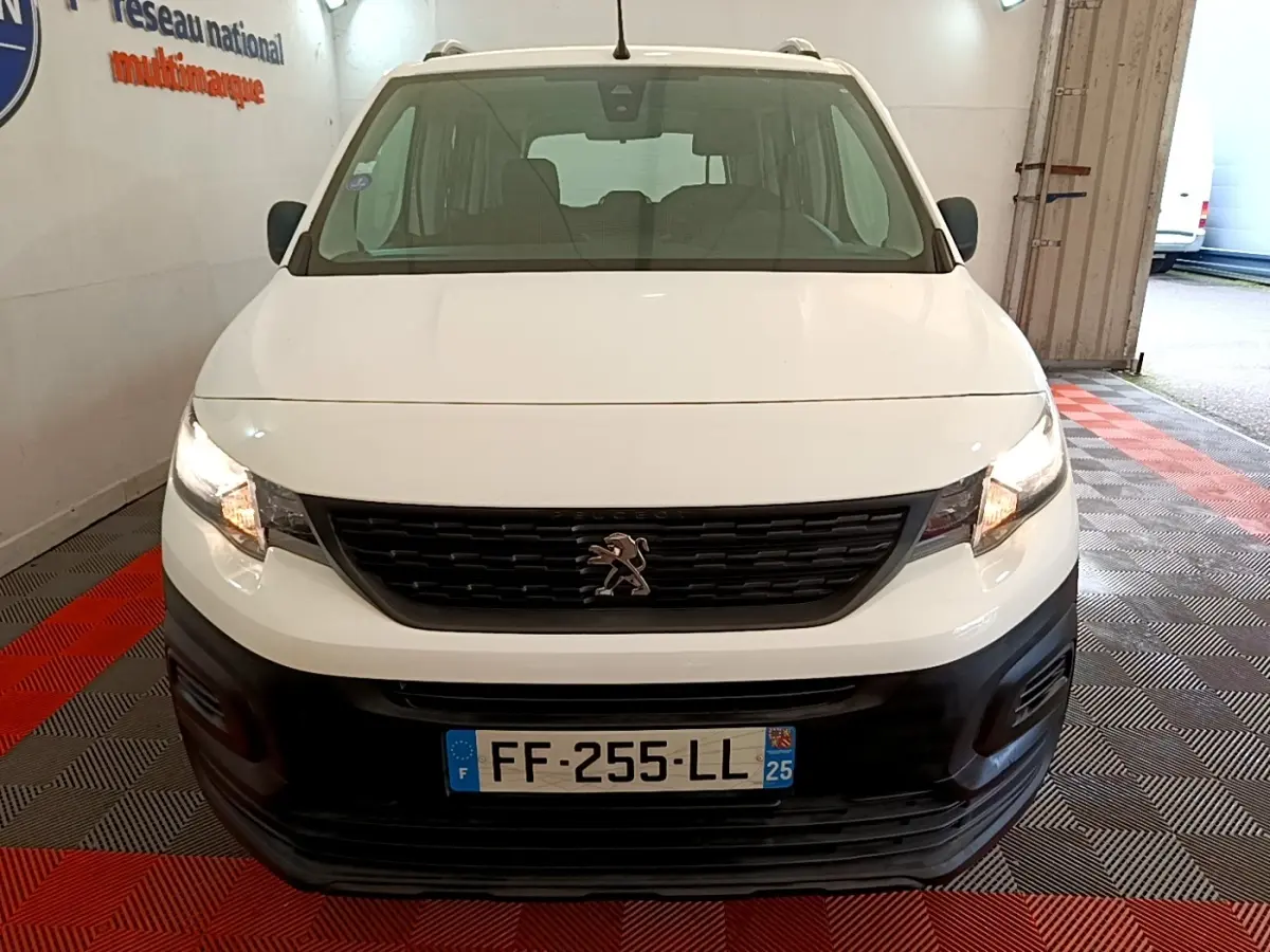 Vue de face d’un Peugeot Rifter blanc 2019 avec calandre noire et phares allumés en intérieur.