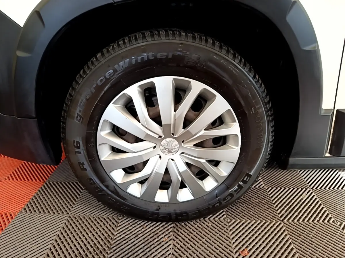 Gros plan sur la roue avant gauche du Peugeot Rifter blanc, avec jante en alliage et pneu hiver visible.