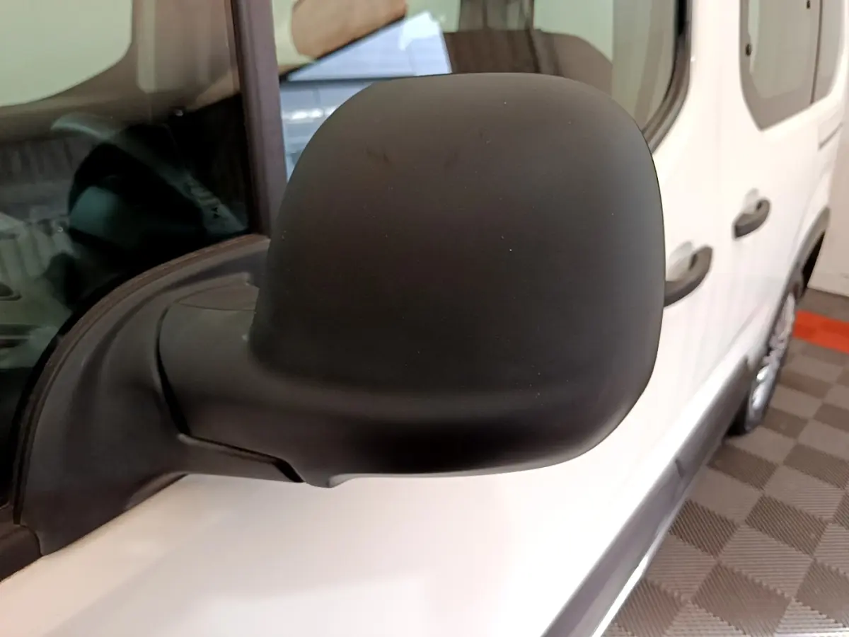 Rétroviseur noir côté conducteur d'un Peugeot Rifter blanc 2019, vue rapprochée sur la portière avant.