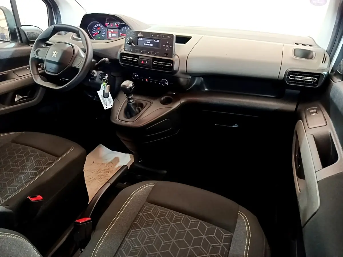 Vue intérieure avant droite du Peugeot Rifter 2019, tableau de bord gris clair et sièges noirs avec motifs géométriques.