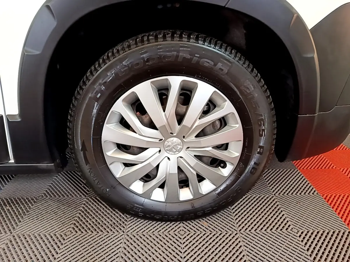 Gros plan sur la roue avant droite du Peugeot Rifter blanc, mettant en valeur la jante argentée et le pneu BFGoodrich.