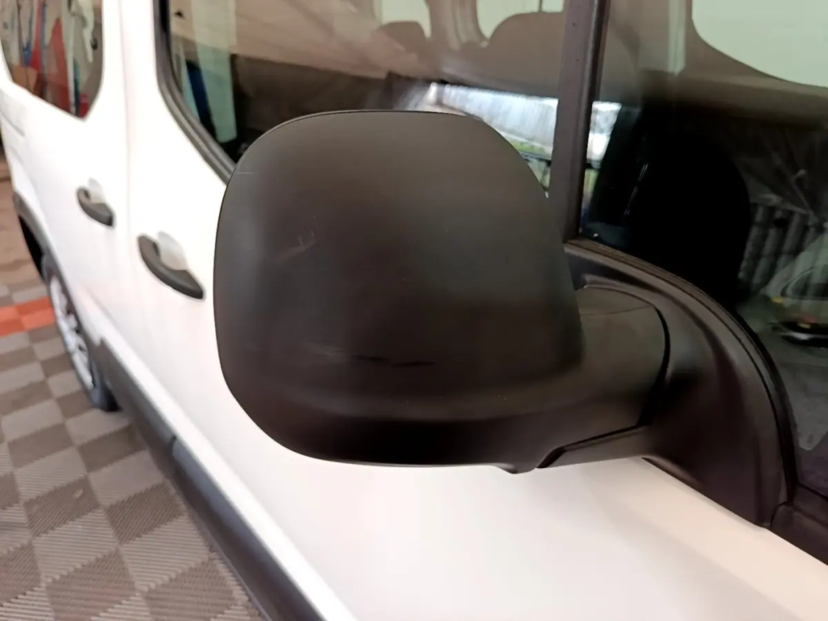 Gros plan sur le rétroviseur noir côté conducteur du Peugeot Rifter blanc, vue latérale avant gauche.