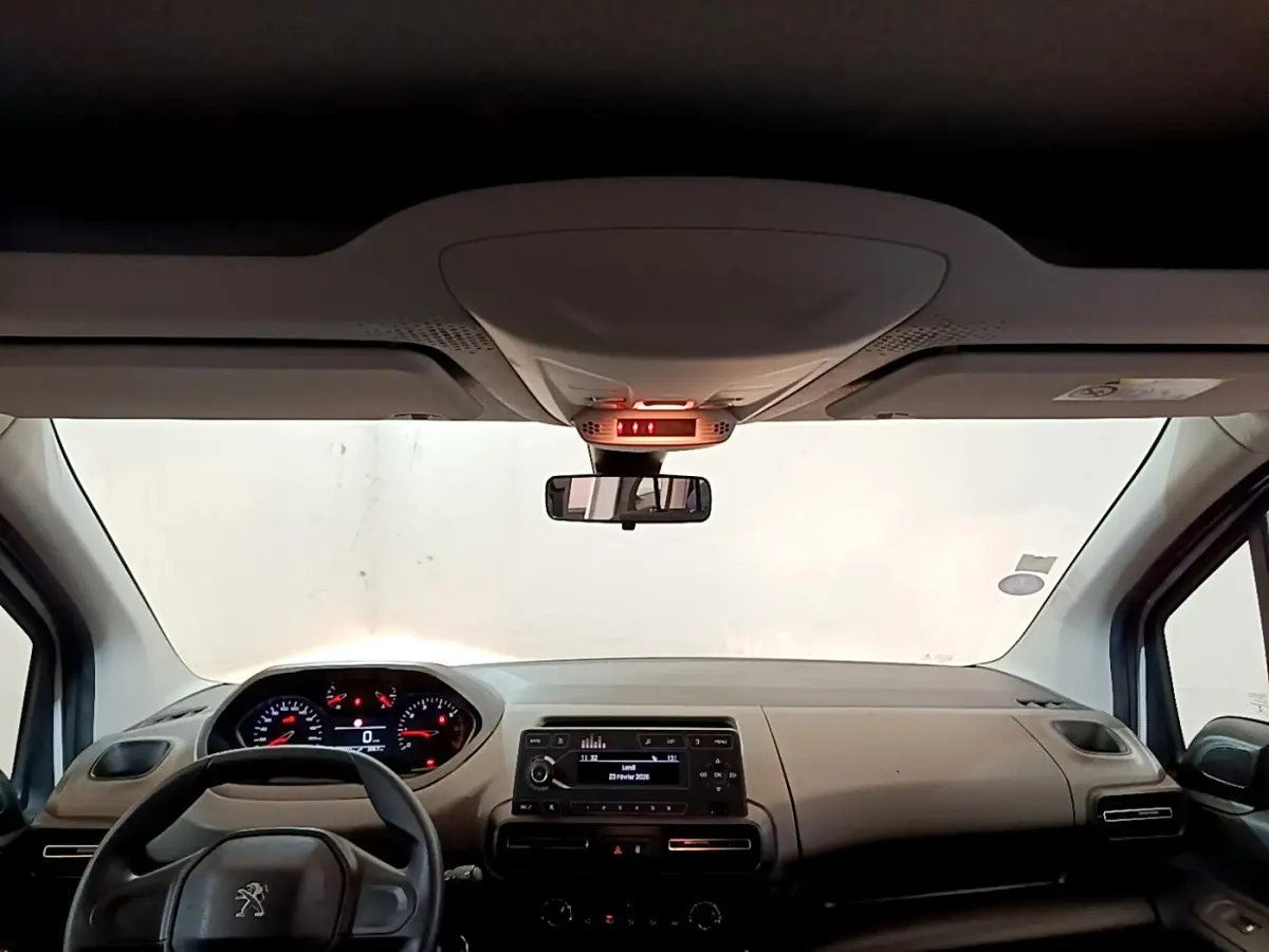 Vue intérieure avant du Peugeot Rifter 2019, tableau de bord beige avec volant noir et écran central allumé.