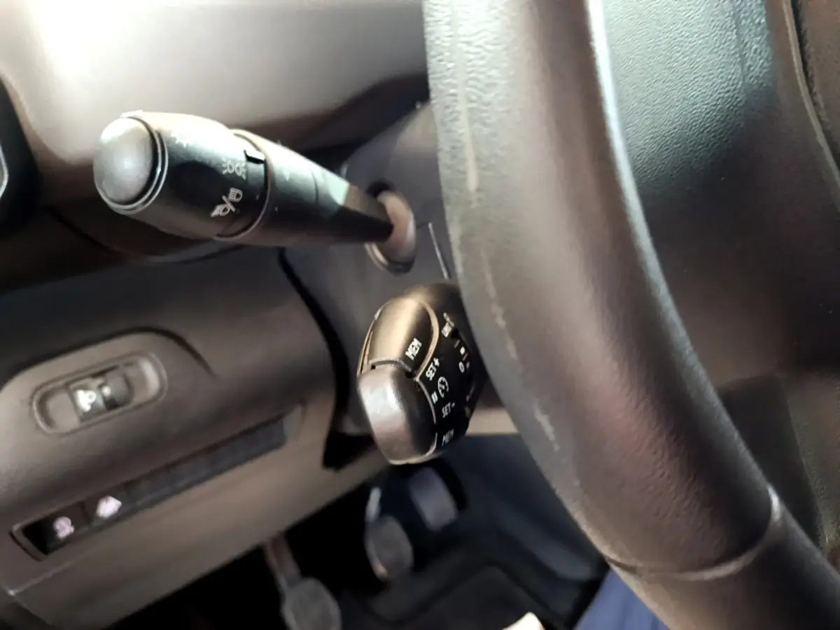 Gros plan sur la colonne de direction et les commandes derrière le volant du Peugeot Rifter blanc, version PureTech 110 S&S Active.