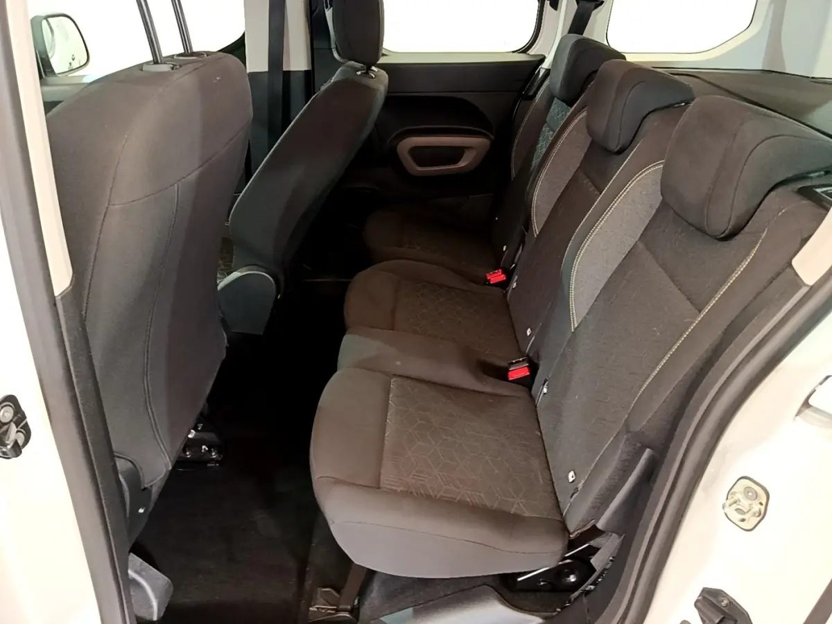 Vue intérieure côté droit sur la banquette arrière noire du Peugeot Rifter blanc, montrant les sièges et appuie-têtes.