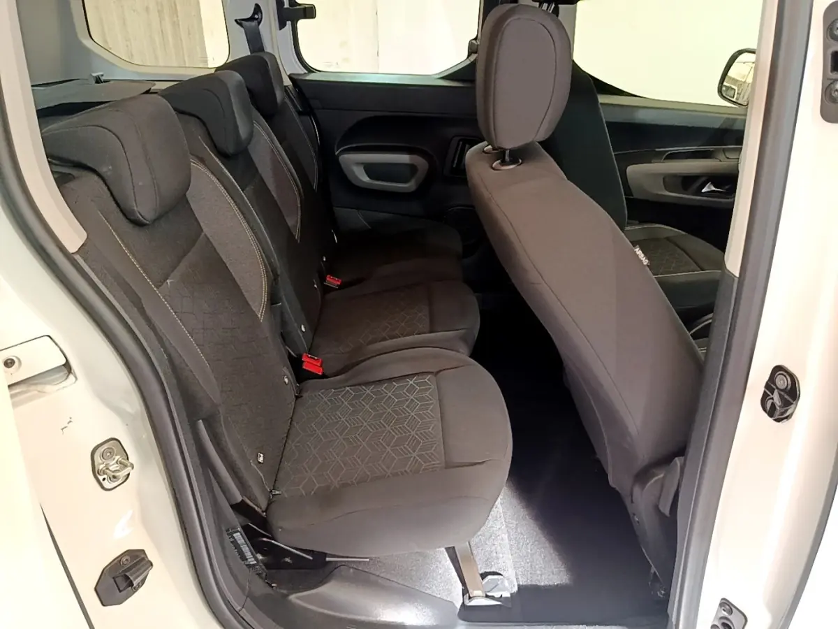 Vue intérieure côté gauche montrant la banquette arrière noire du Peugeot Rifter blanc, porte arrière ouverte.