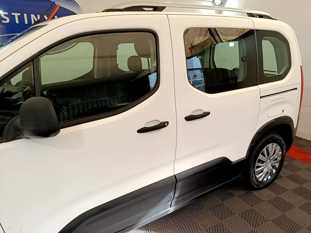 Vue latérale droite du Peugeot Rifter blanc avec protections noires sur les bas de caisse et jantes argentées.