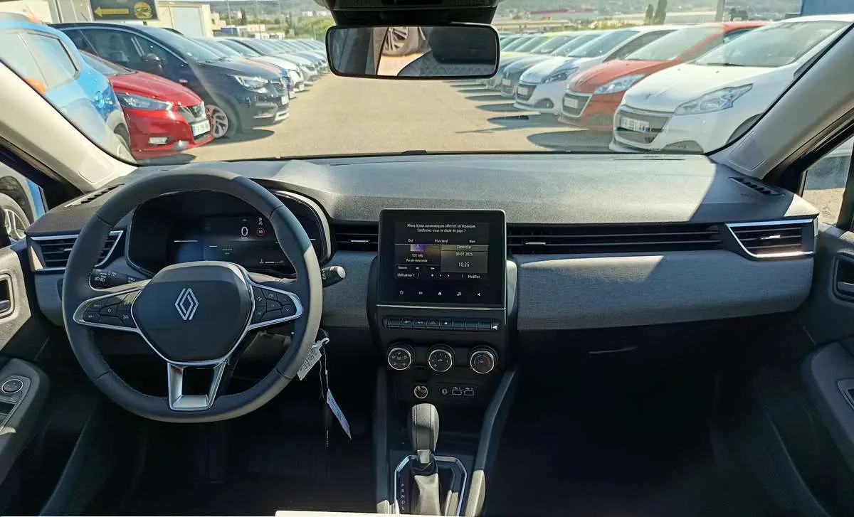 Vue intérieure frontale du tableau de bord et volant de la Renault Clio gris schiste 2025 avec écran tactile central et boîte auto.