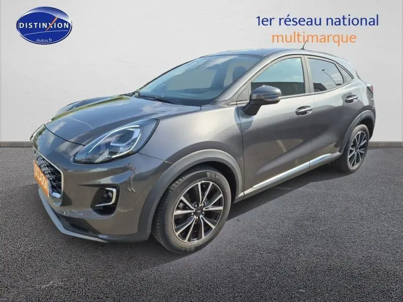 Ford Puma 1.0 EcoBoost gris métallisé en 3/4 avant droit, avec jantes alu et phares LED visibles.