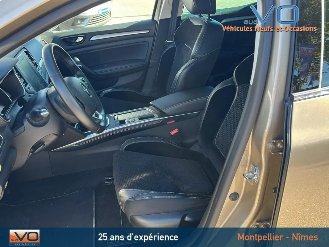 Vue intérieure côté conducteur d'une Renault Mégane IV beige de 2017, sièges noirs et tableau de bord moderne.