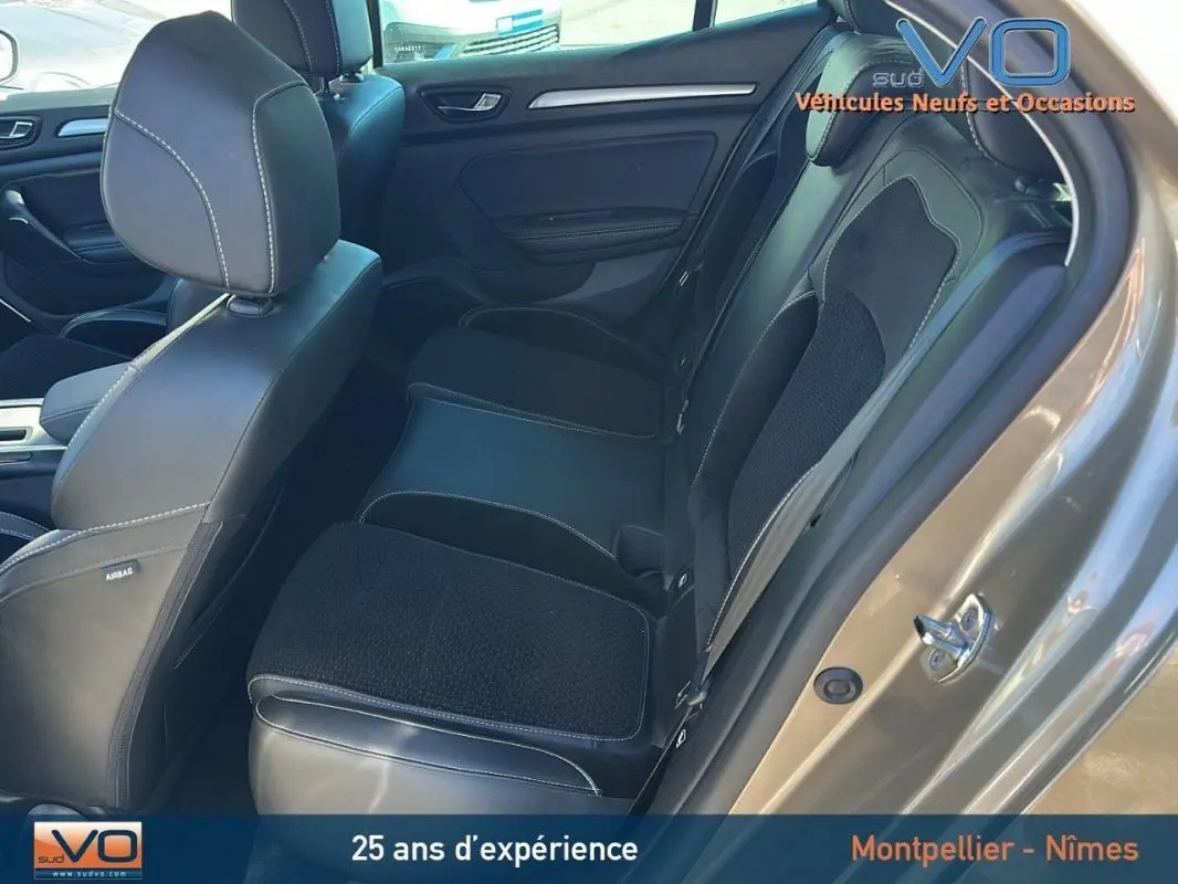 Vue intérieure côté arrière droit de la Renault Mégane IV beige, montrant les sièges en cuir et tissu noir.