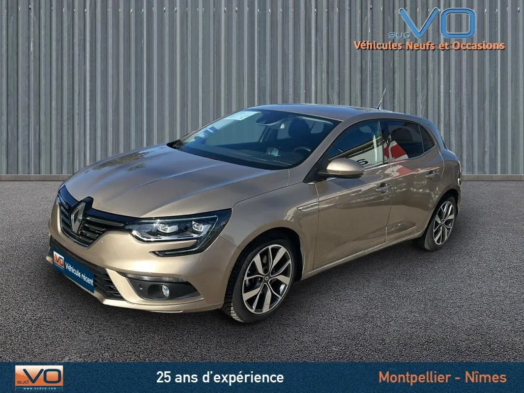 Renault Mégane IV beige vue 3/4 avant droit, avec jantes alliage et phares LED allumés sur fond urbain.