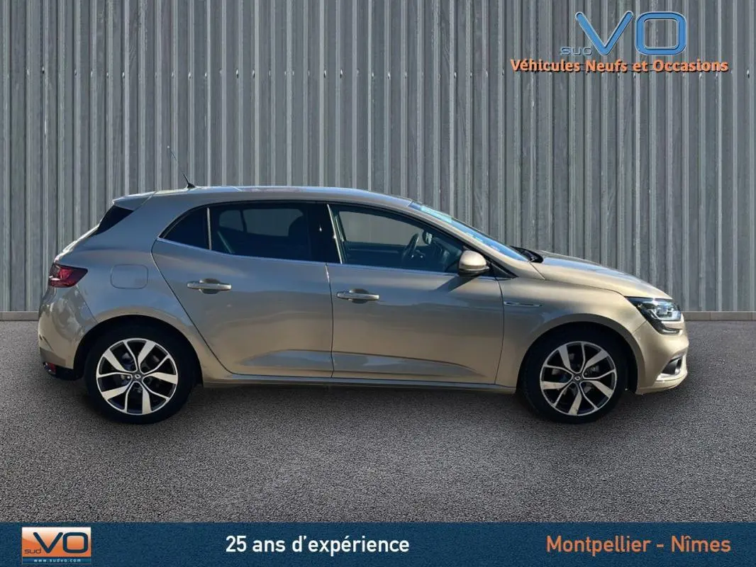 Profil côté gauche d'une Renault Mégane IV beige 2017, berline compacte avec jantes alliage et vitres teintées.