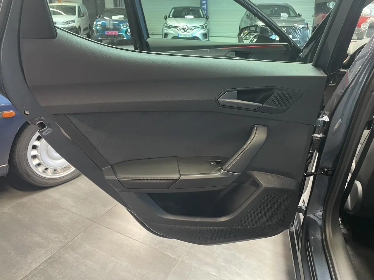 Contre-porte arrière droite de la CUPRA Leon gris magnetic, avec poignée intégrée et finition noire texturée.