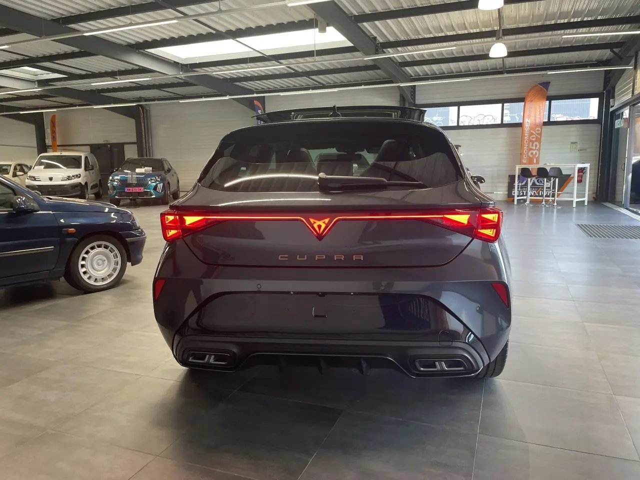 Vue arrière d'une CUPRA Leon gris magnétique avec feux arrière Tri-LED et double sortie d'échappement stylisée.