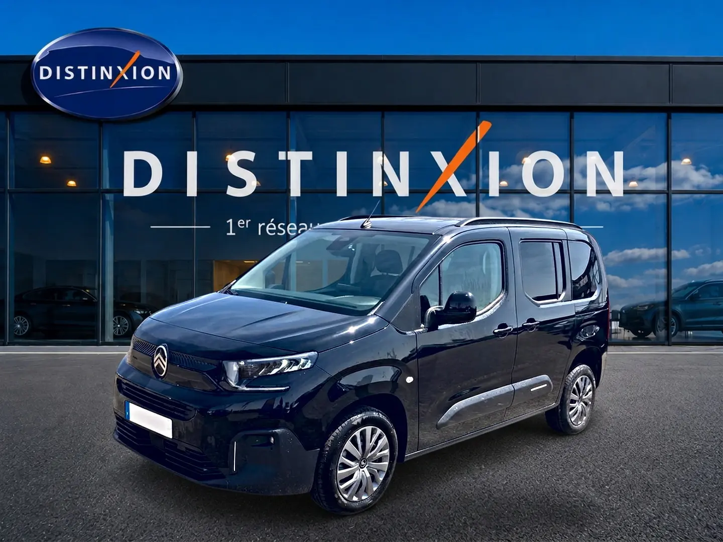 Citroën Berlingo noir vue 3/4 avant droit, avec barres de toit et jantes alu devant showroom Distinxion.