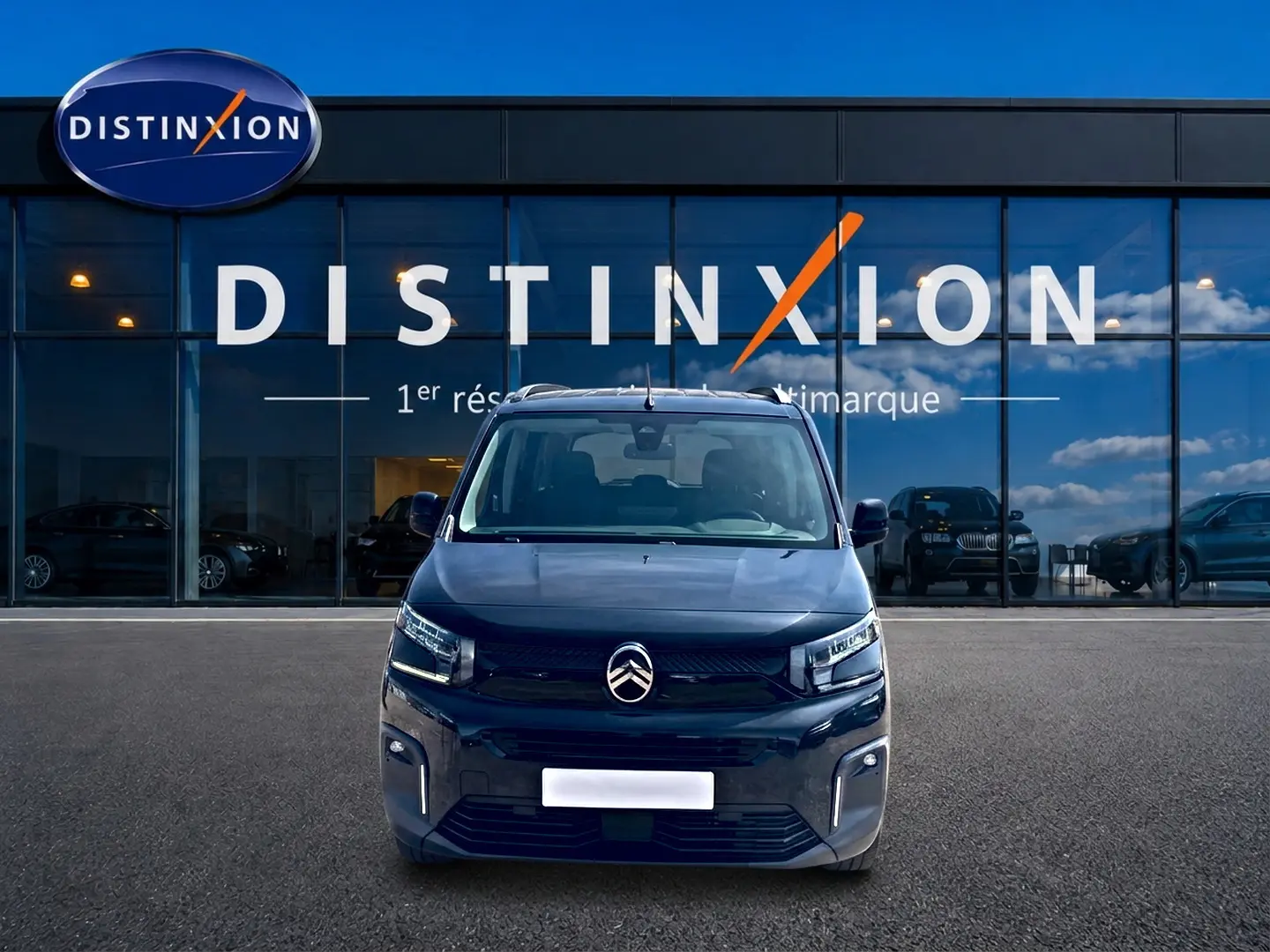 Vue avant centrée du Citroën Berlingo noir 2026 avec phares LED et logo distinctif sur fond vitré d'un showroom.