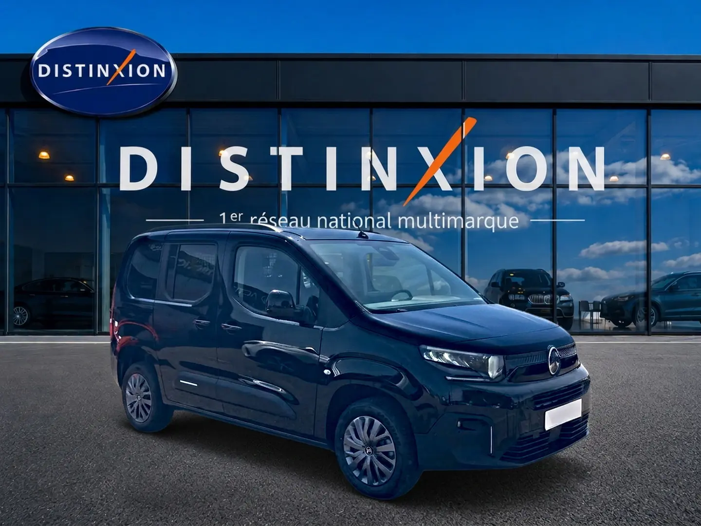 Vue 3/4 avant droite du Citroën Berlingo noir 2026, avec jantes alu et porte latérale visible devant un showroom Distinxion.