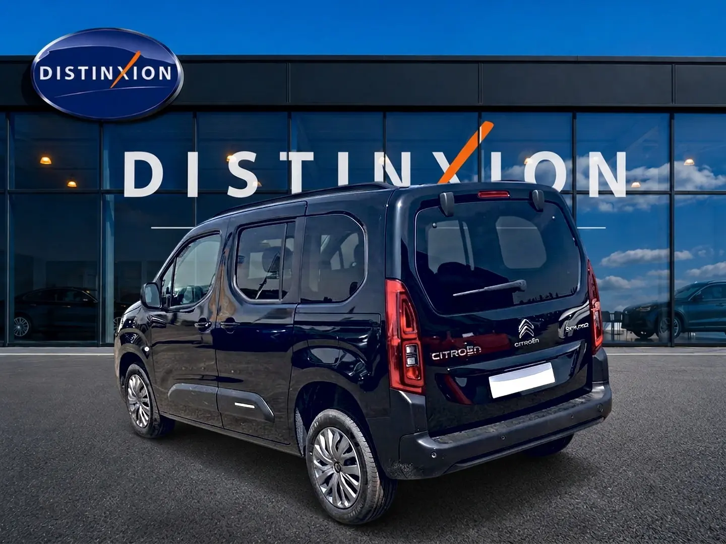 Vue 3/4 arrière droite d’un Citroën Berlingo noir 2026 avec vitres teintées et jantes alu devant un showroom.
