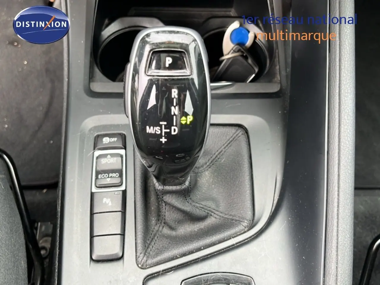 Gros plan sur le levier de vitesses automatique noir du BMW X1 18i gris argent, avec boutons mode Sport et Eco Pro visibles.