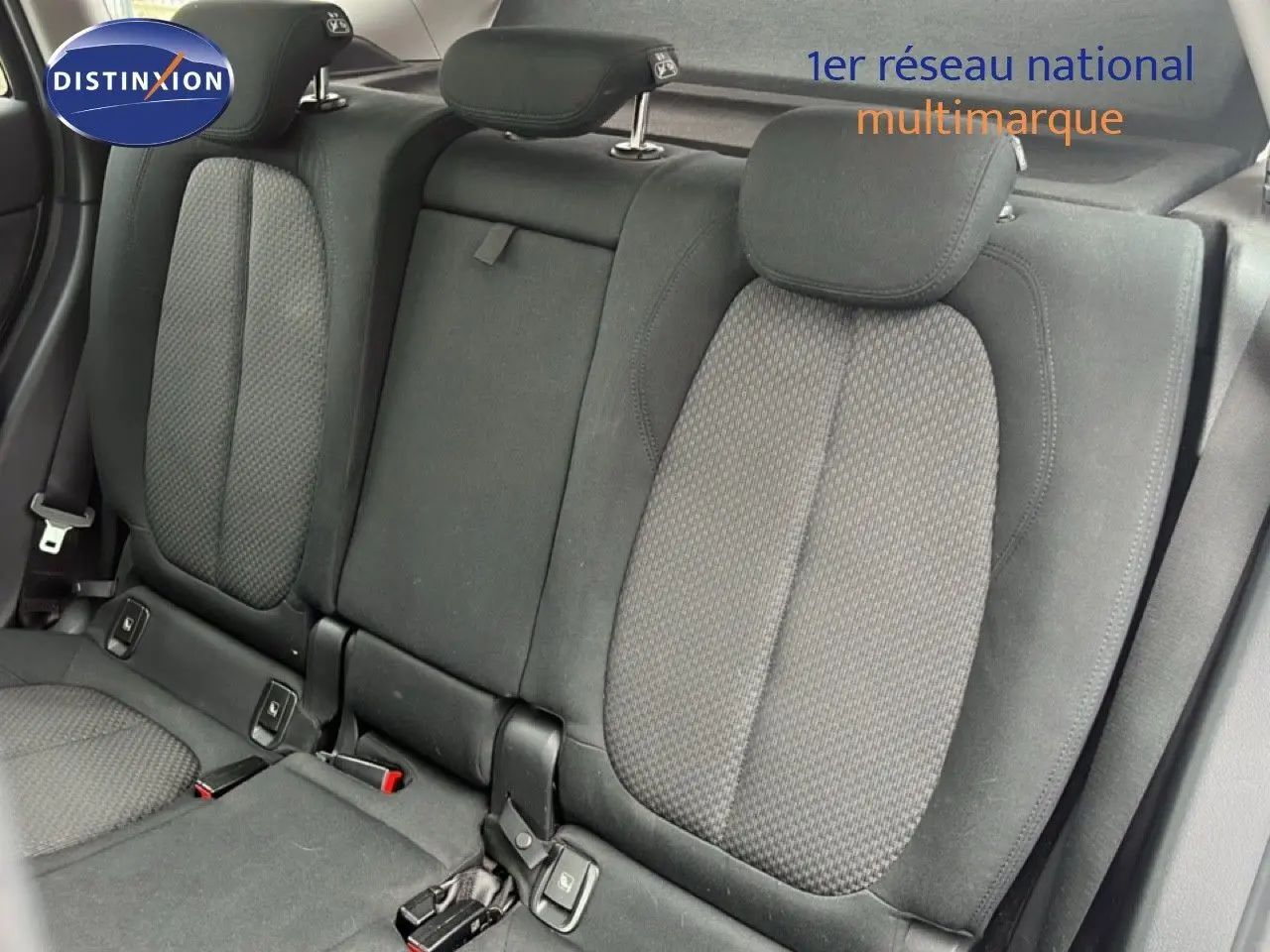 Vue intérieure sur les sièges arrière en tissu gris noir du BMW X1 18i 2018, avec appuie-têtes et ceintures visibles.