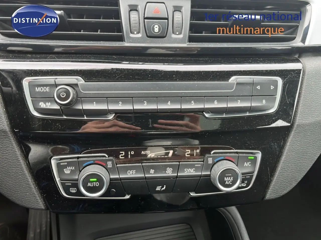 Vue rapprochée de la console centrale noire du BMW X1 18i 2018, avec commandes climatisation et multimédia.