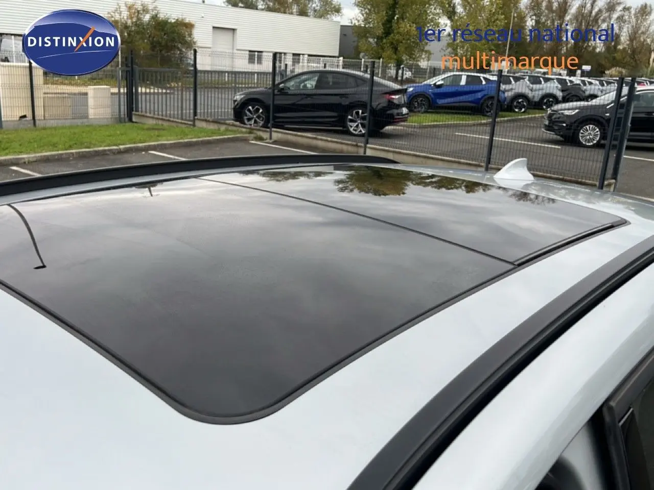 Toit ouvrant panoramique en verre sur BMW X1 gris argent métal, vue en léger plongé depuis l'arrière droit.