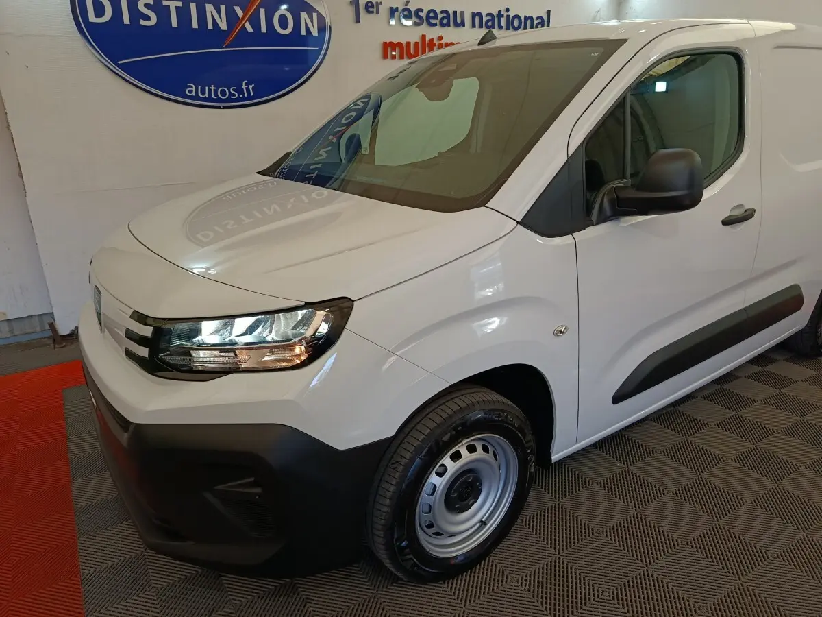 Vue 3/4 avant droit d'un utilitaire Peugeot Partner blanc avec pare-chocs noirs et jantes acier grises.