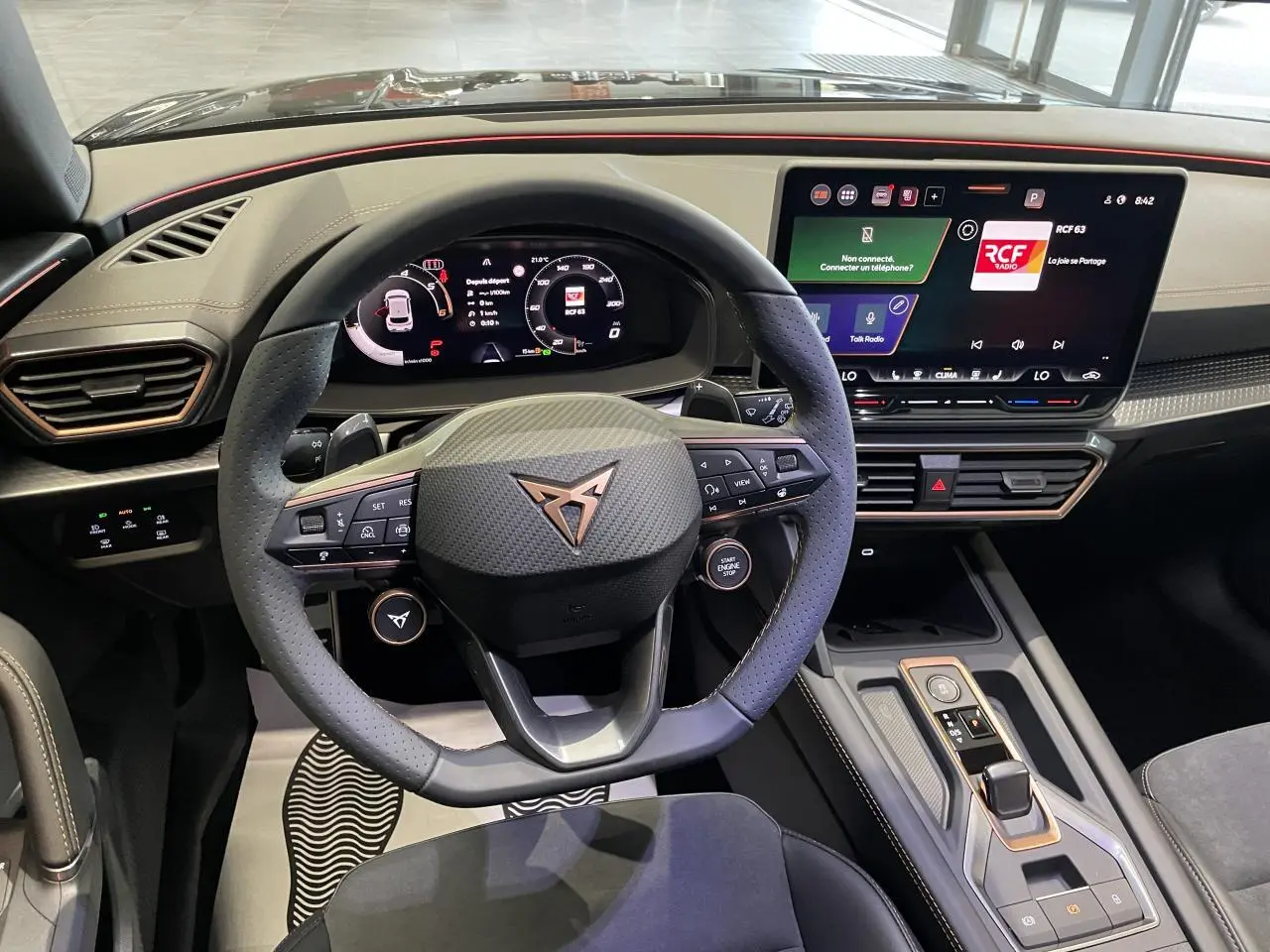 Intérieur CUPRA Leon 2026 vu du poste de conduite, volant cuir noir avec logo cuivré et écran tactile HD 12,9 pouces.
