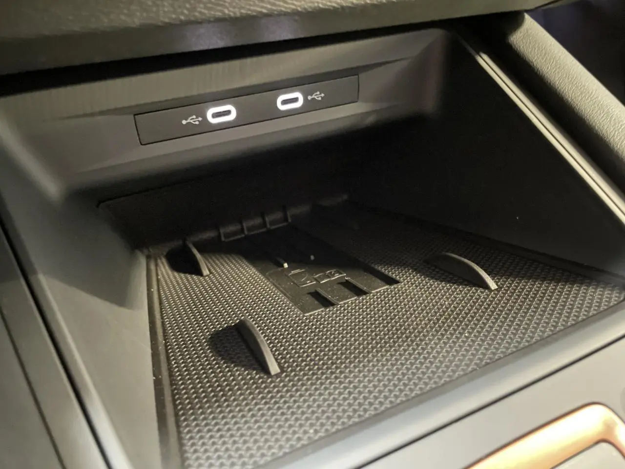 Gros plan sur la zone de recharge et ports USB-C éclairés du coffre à objets de la CUPRA Leon noire 2026.