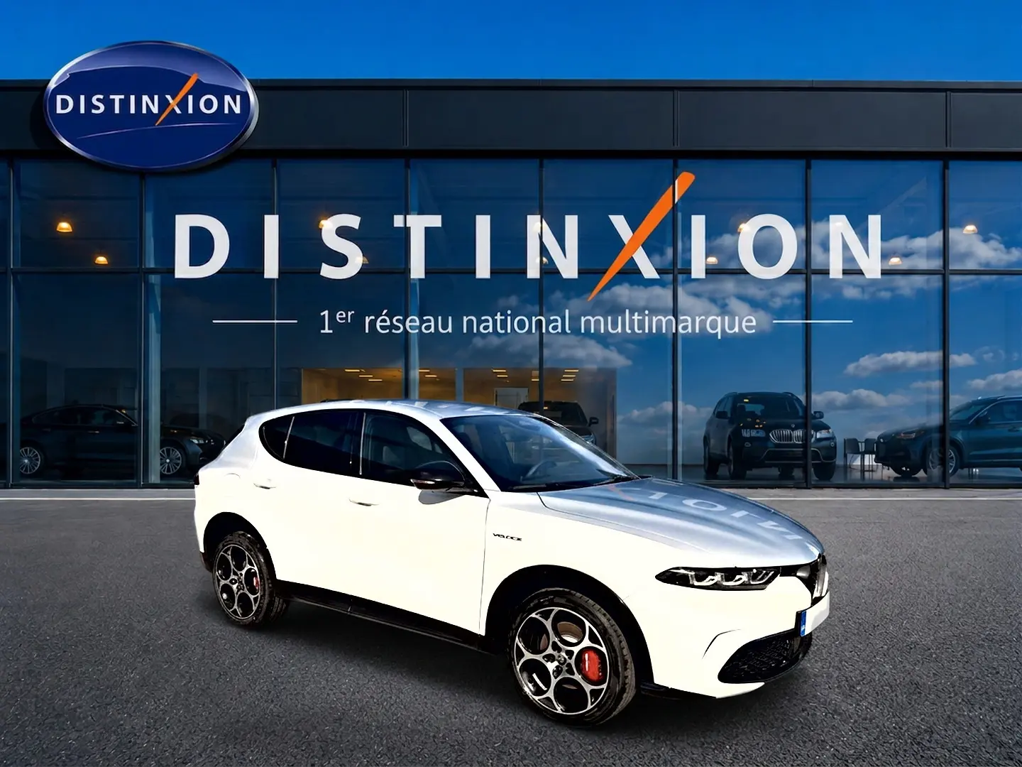 Alfa Romeo Tonale blanc en 3/4 avant droit, jantes alu distinctives et calandre noire, devant vitrine Distinxion.