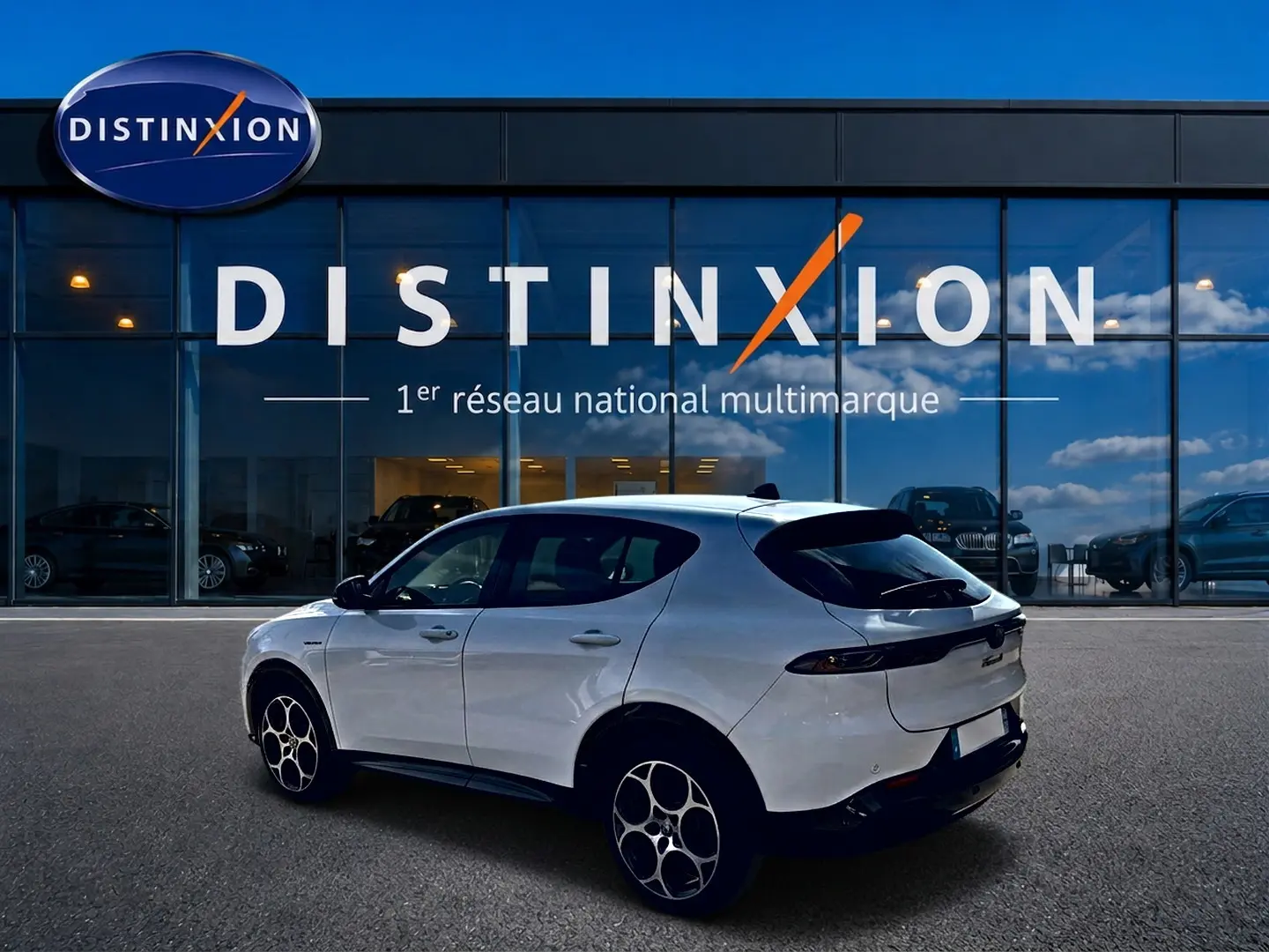 Alfa Romeo Tonale blanc en 3/4 arrière droit, avec jantes alu distinctives, devant un showroom Distinxion.