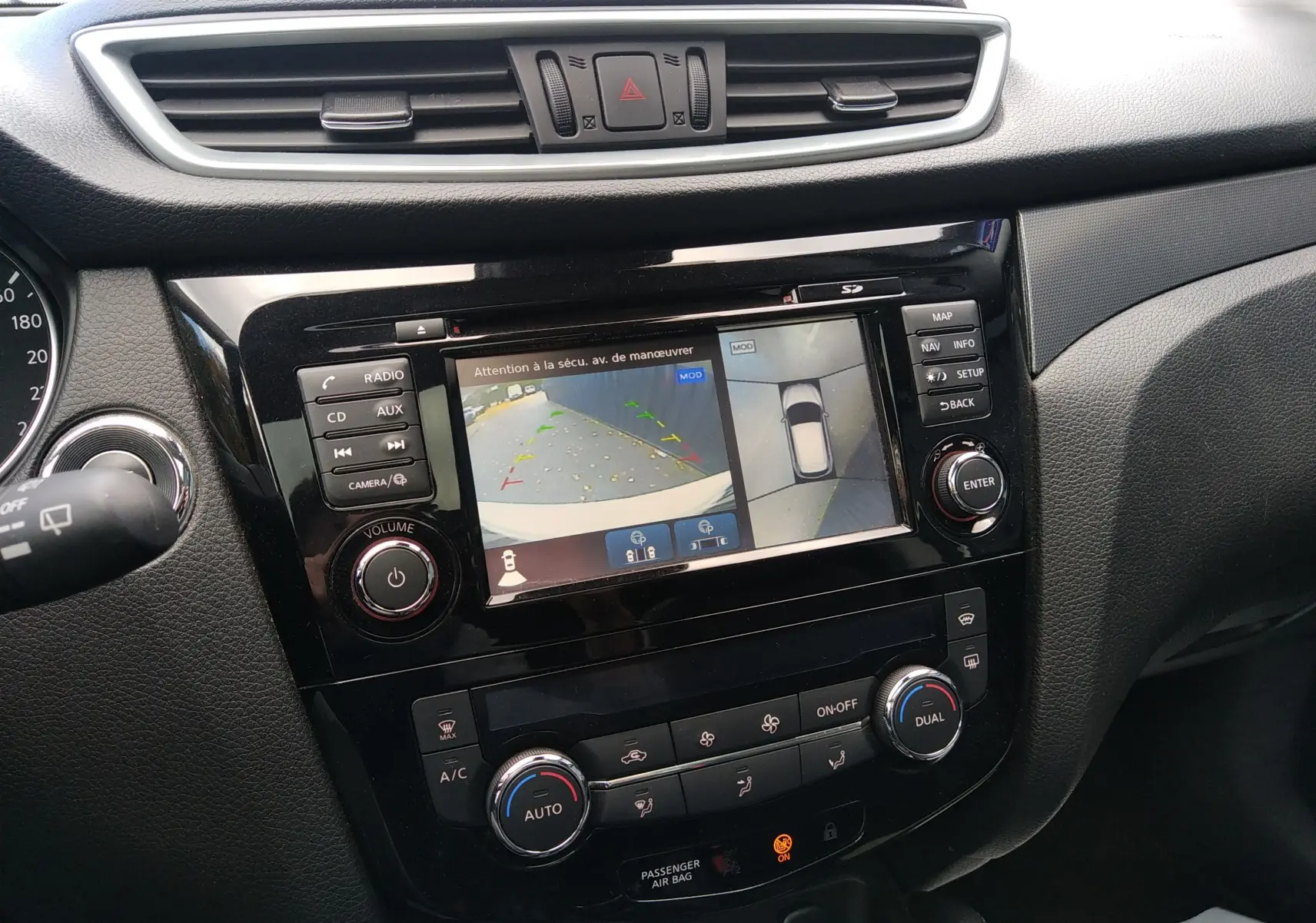 Vue rapprochée de la console centrale noire du Nissan Qashqai 2018 avec écran multifonction affichant la caméra de recul.