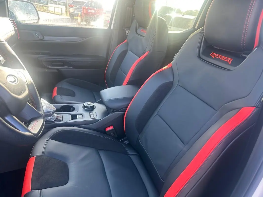 Vue intérieure côté conducteur du Ford Ranger Raptor 2025 avec sièges sport noirs et rouges brodés "Raptor".