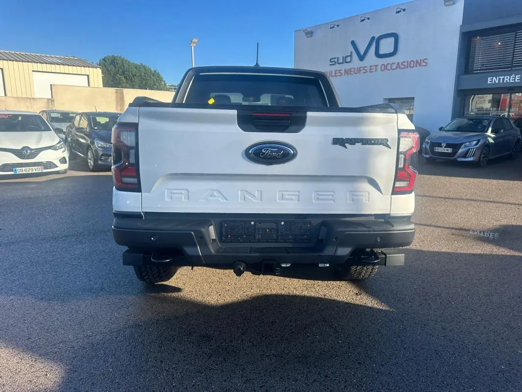 Vue arrière d'un Ford Ranger Raptor blanc 2025 avec hayon marqué Ranger et feux arrière LED distinctifs.