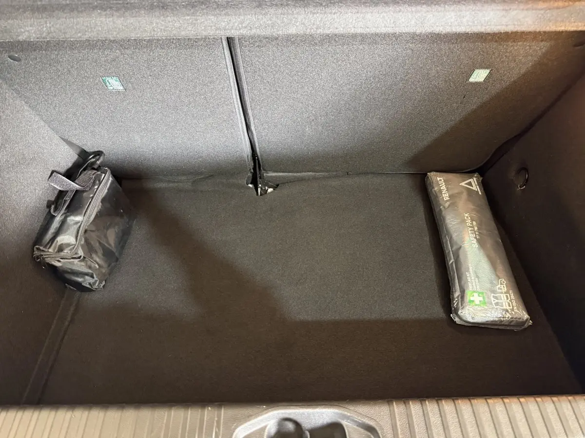 Vue intérieure du coffre noir de la Renault Clio Business TCe 100 GPL avec trousse de secours et kit de sécurité.