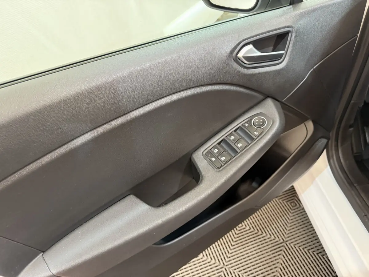 Vue intérieure côté gauche de la porte avant d'une Renault Clio blanche, avec commandes électriques des vitres et poignée intégrée.