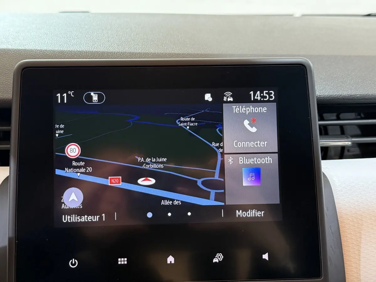 Écran tactile central de la Renault Clio Business blanc, affichant navigation 3D et options Bluetooth à l'avant.