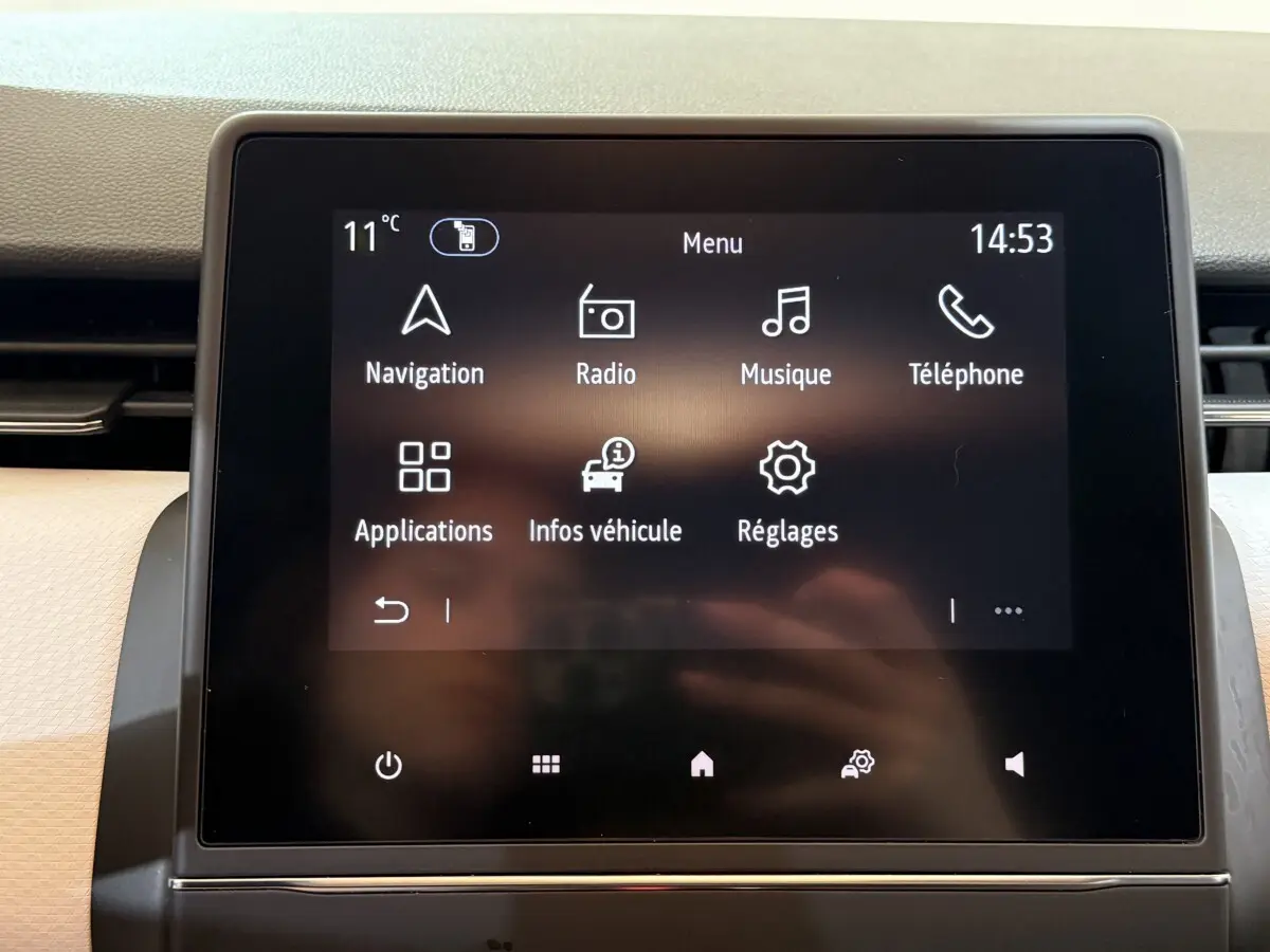 Écran tactile central de la Renault Clio Business blanc, affichant le menu principal avec navigation et musique.