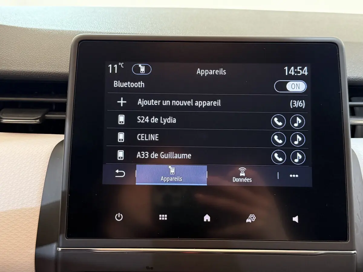 Écran tactile central affichant la connexion Bluetooth dans l’habitacle clair d’une Renault Clio blanche.
