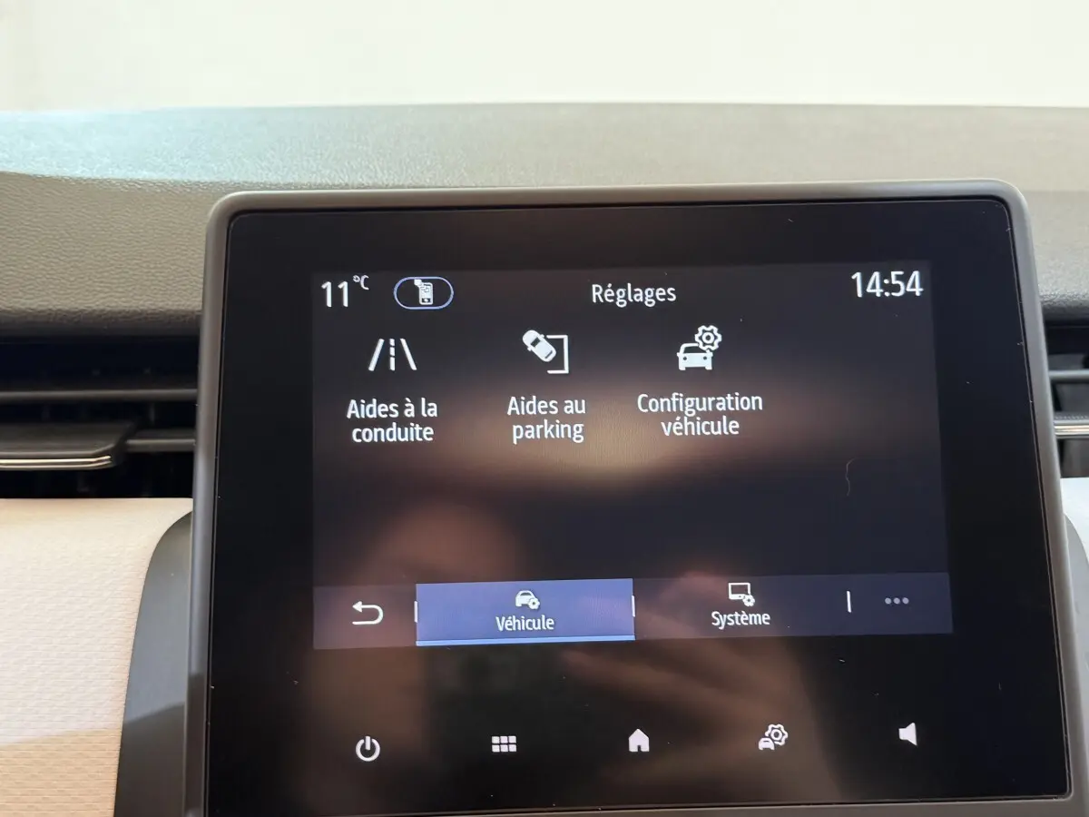 Écran tactile central de la Renault Clio Business blanc, affichant les réglages d’aides à la conduite et parking.