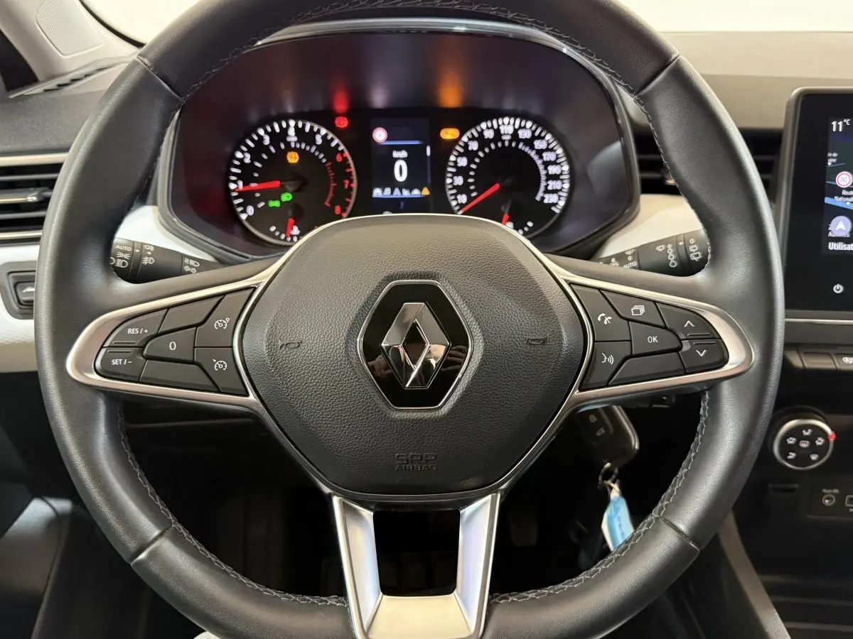 Vue rapprochée du volant cuir noir de la Renault Clio Business 2022 avec tableau de bord et commandes visibles.